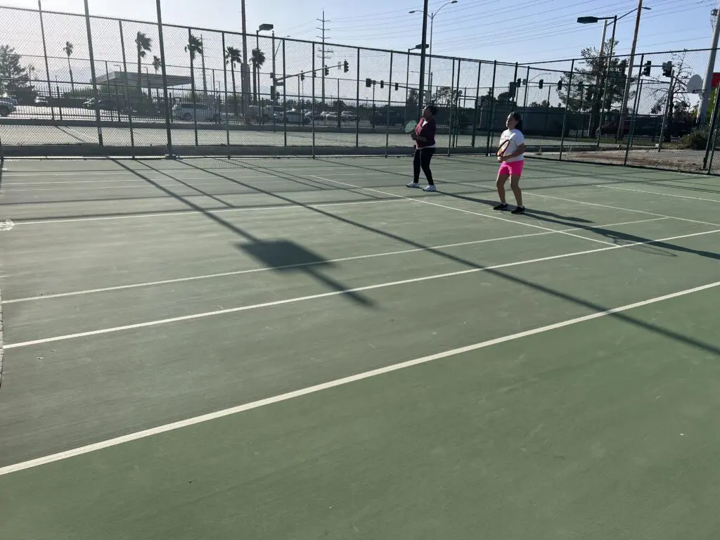 Two Women Playing on a Tennis Ground With Nets